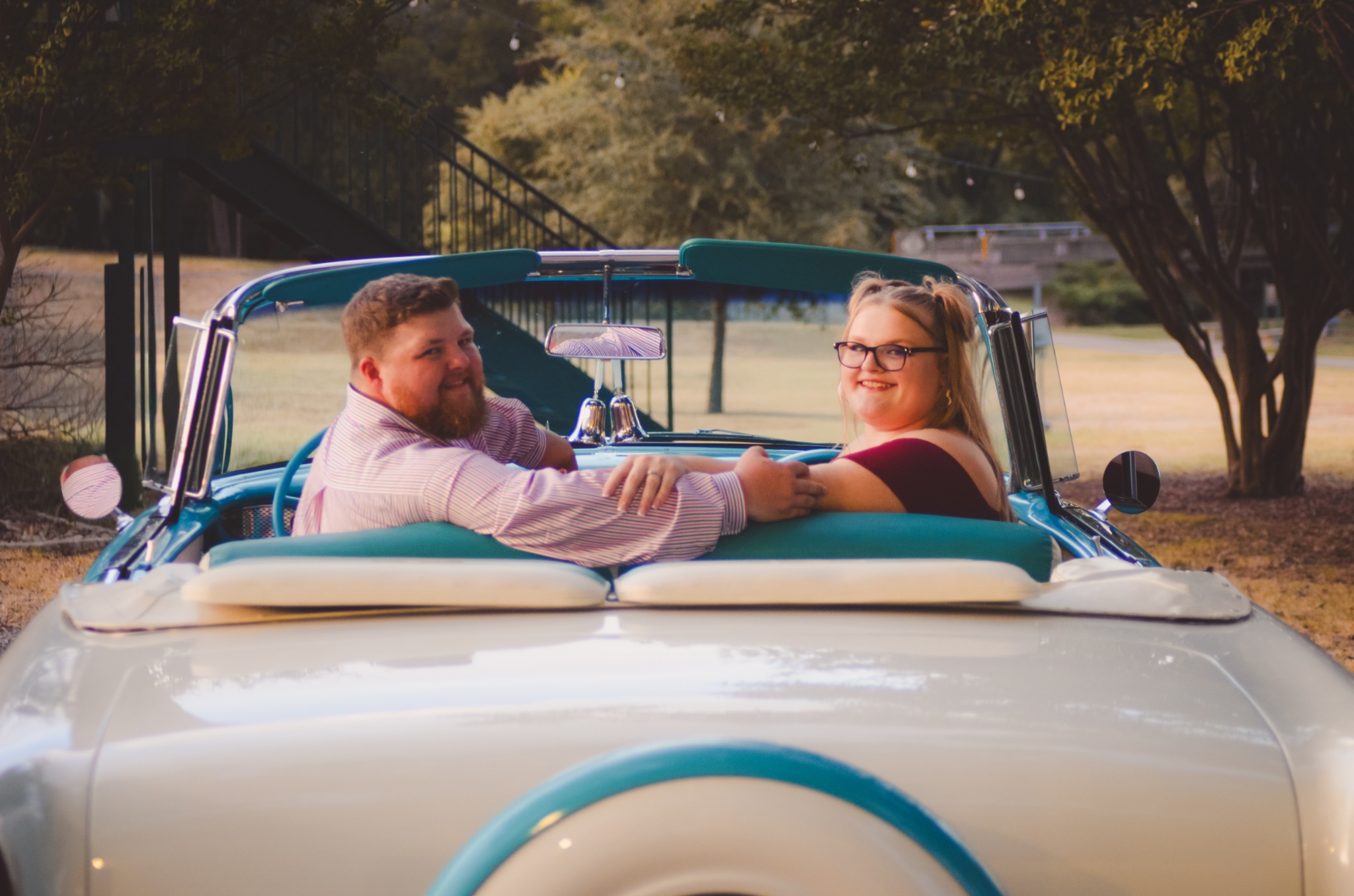Engaged couple looking back from the back seat of Ole' Belle
