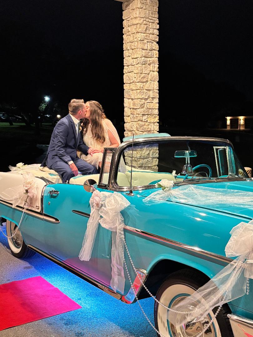 Newlyweds sharing a kiss while seated in Ole' Belle