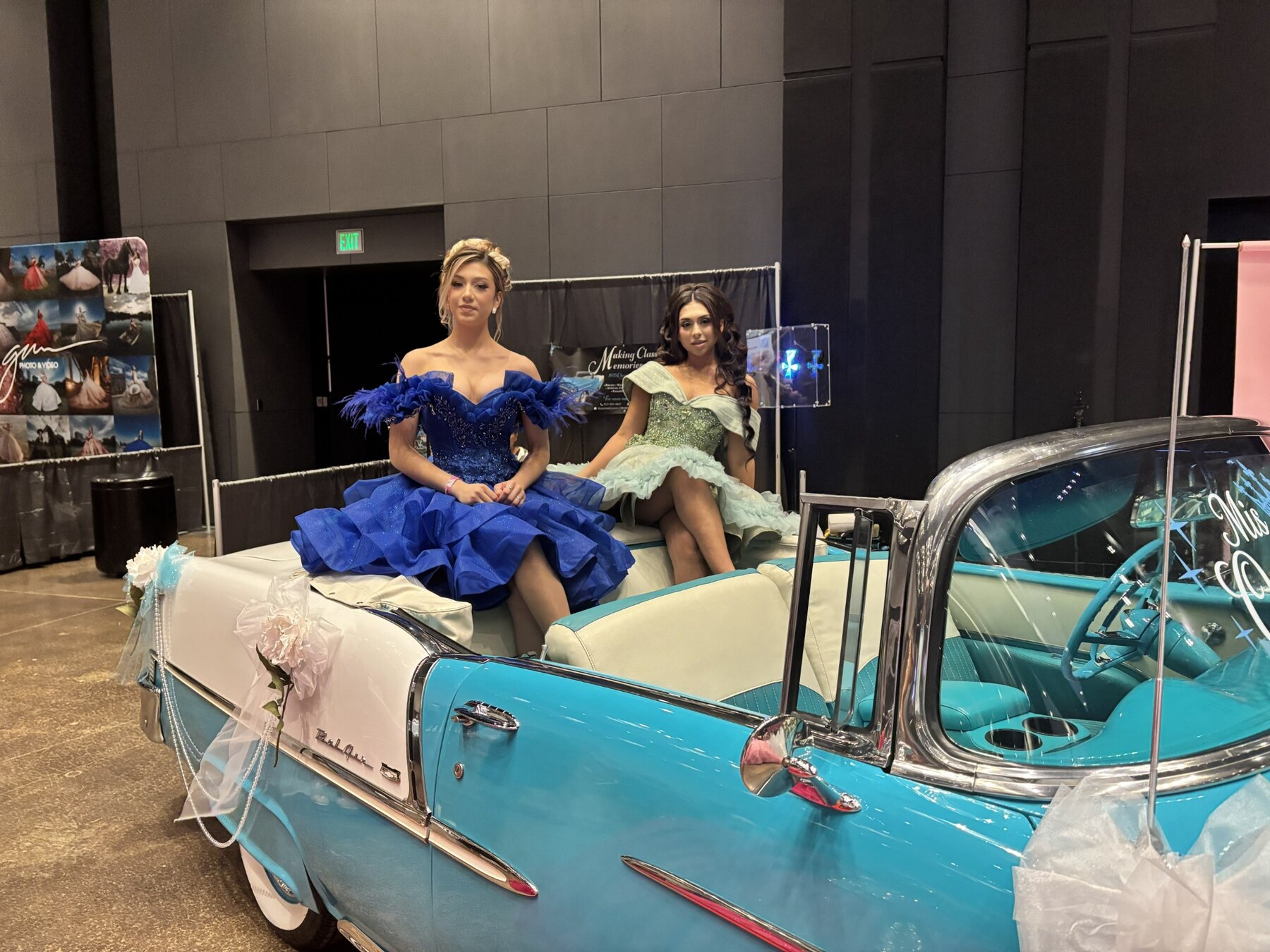 Two young women in blue quinceañera gowns posing together inside Ole' Belle