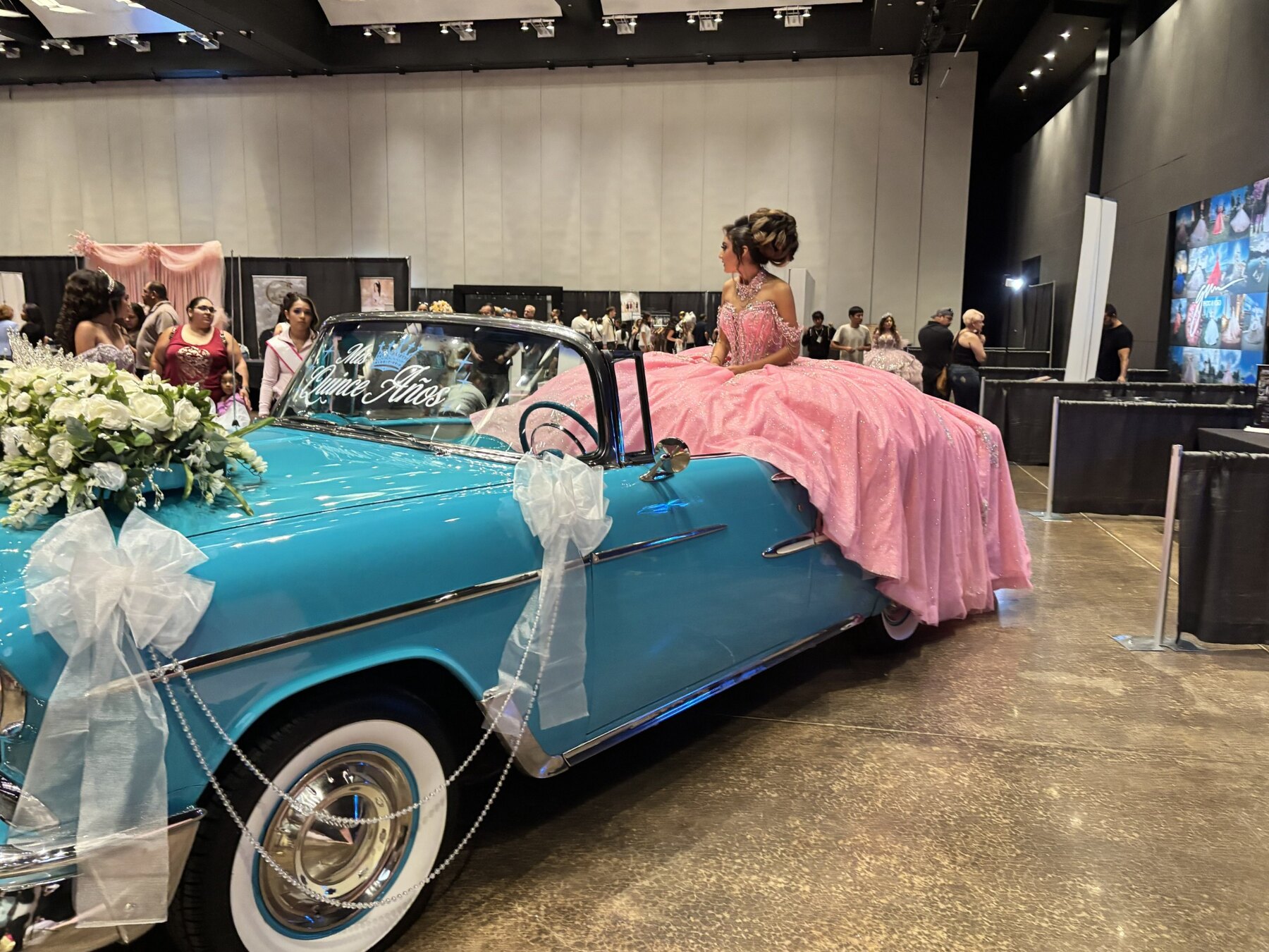 Young woman in a pink quinceañera gown sitting beside Ole' Belle at the Quinceañera Expo